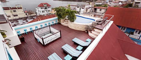 Una terraza en la azotea con tumbonas, una piscina pequeña y vistas a la ciudad y al agua.