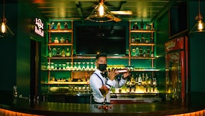 Un bar con estantes llenos de botellas de licor, un letrero de neón y una barra.