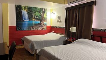 Habitación de hotel con dos camas, un cuadro de una cascada, aire acondicionado, una lámpara y un reloj en la pared.