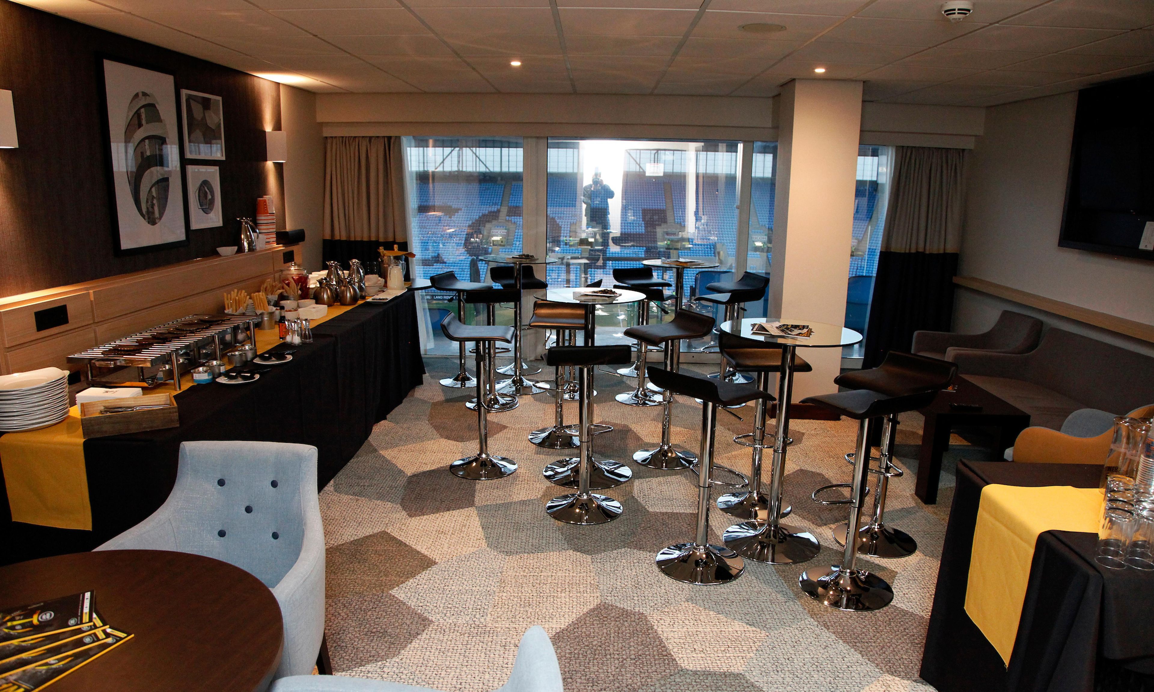 A hotel lobby with a bar area, seating arrangements, and a view of the outside.