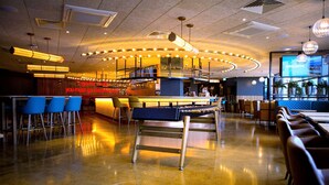 Uma área de bar moderna com balcão alto, banquetas azuis e mesa de bilhar.