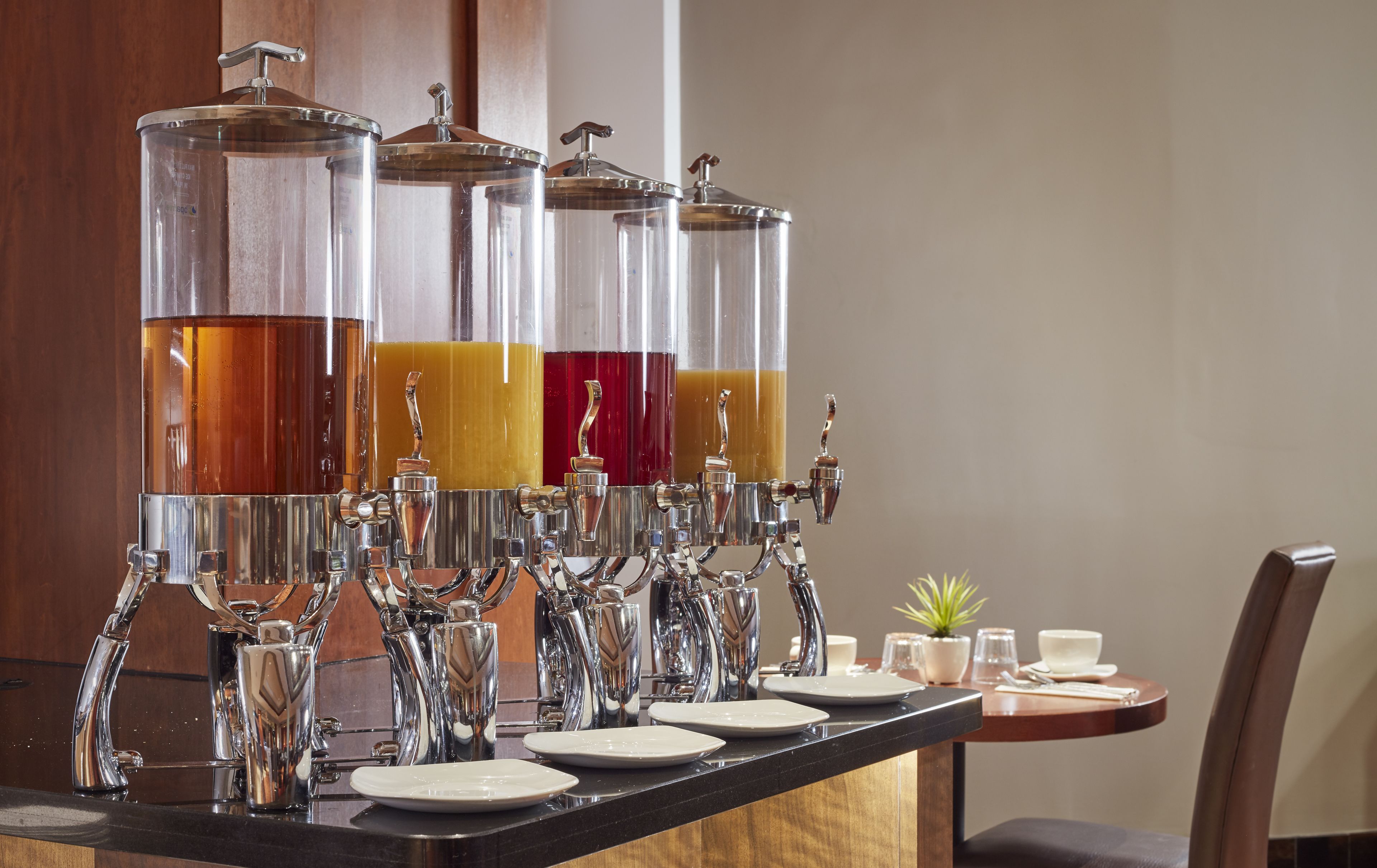 Un espace dédié aux boissons, équipé de plusieurs distributeurs, ainsi qu’une table avec des assiettes et des verres.