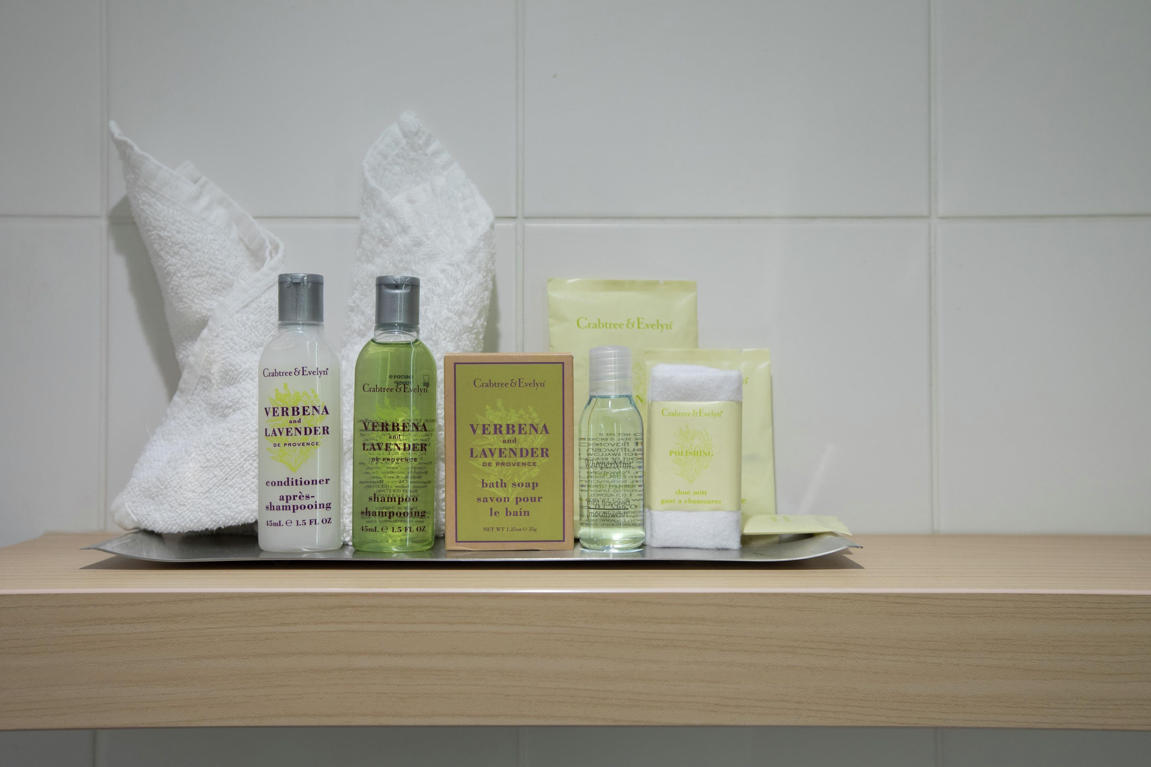A bathroom shelf with various personal care products including a conditioner, shampoo, bath soap, and a polishing spray.