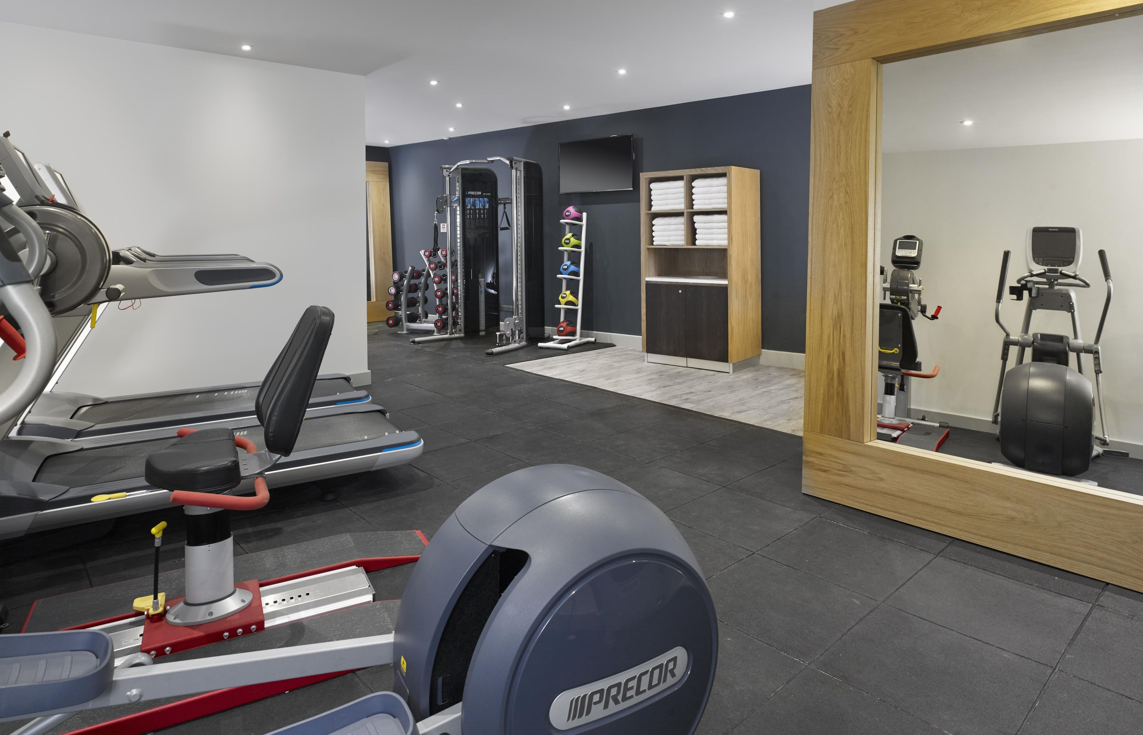 A modern gym with various exercise equipment including treadmills, a weight bench, and free weights.
