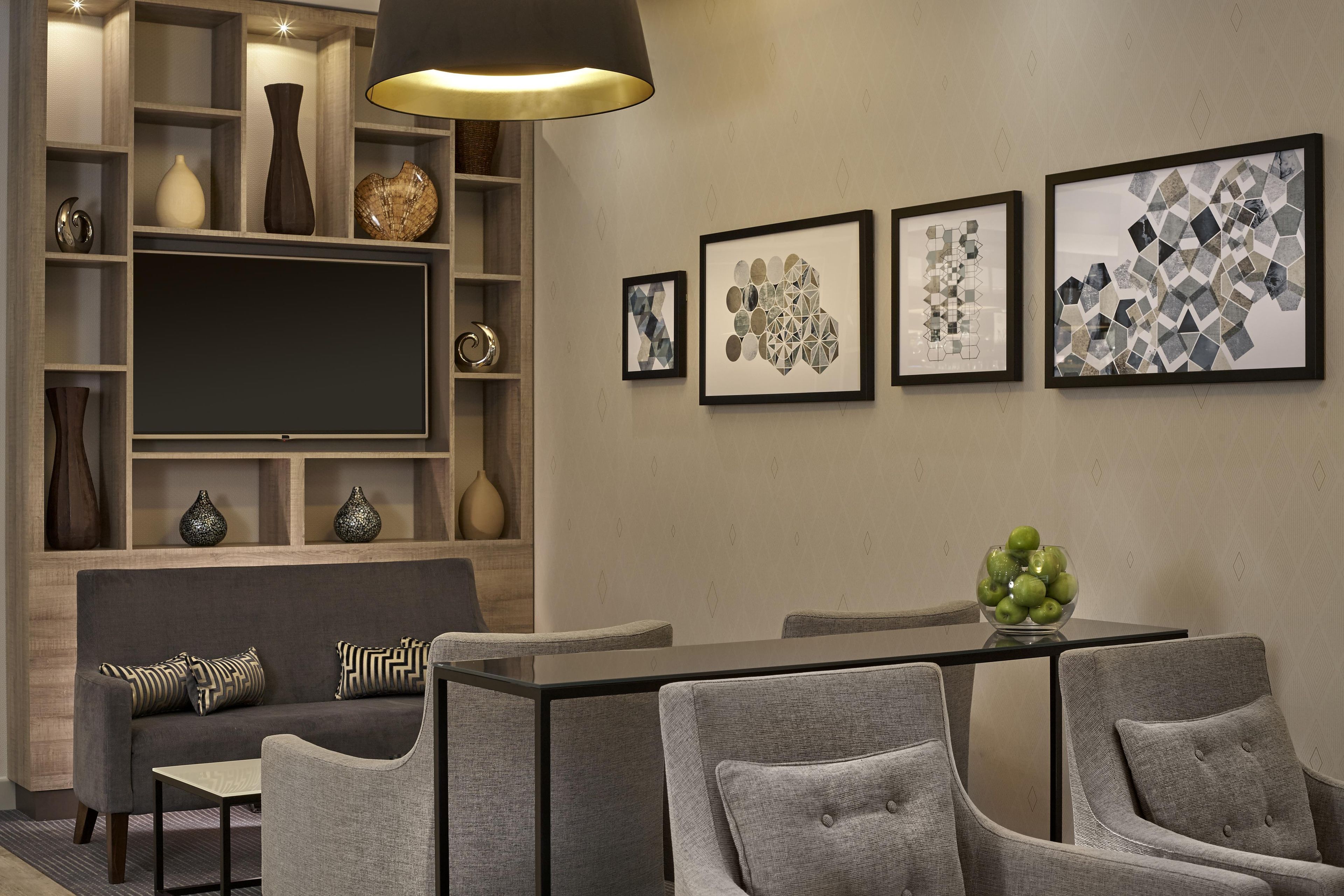 Una sala de estar moderna con sofá, sillas, una mesa de comedor y una televisión.