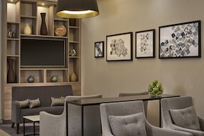 A modern living room with a sofa, chairs, a dining table, and a TV. - DoubleTree by Hilton Coventry Building Society Arena (Coventry)