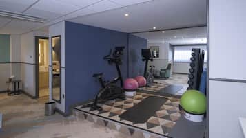 Ett gym med träningsutrustning, en spegel och ett mönstrat golv.