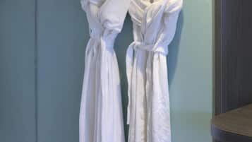 Two white robes hanging on a wall in a room with a tiled floor.
