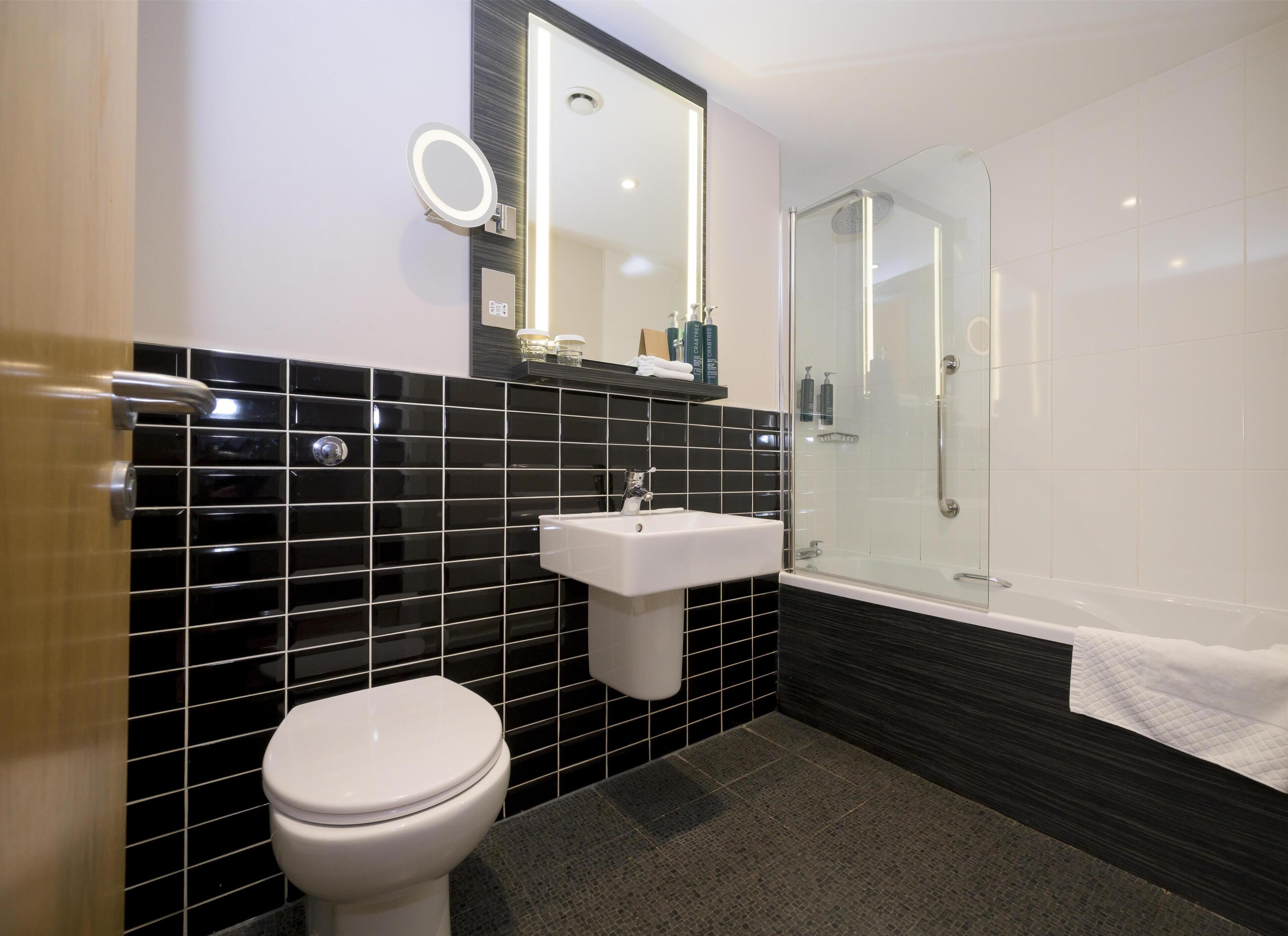 Une salle de bain équipée de toilettes, d’un lavabo et d’une douche à parois de verre.