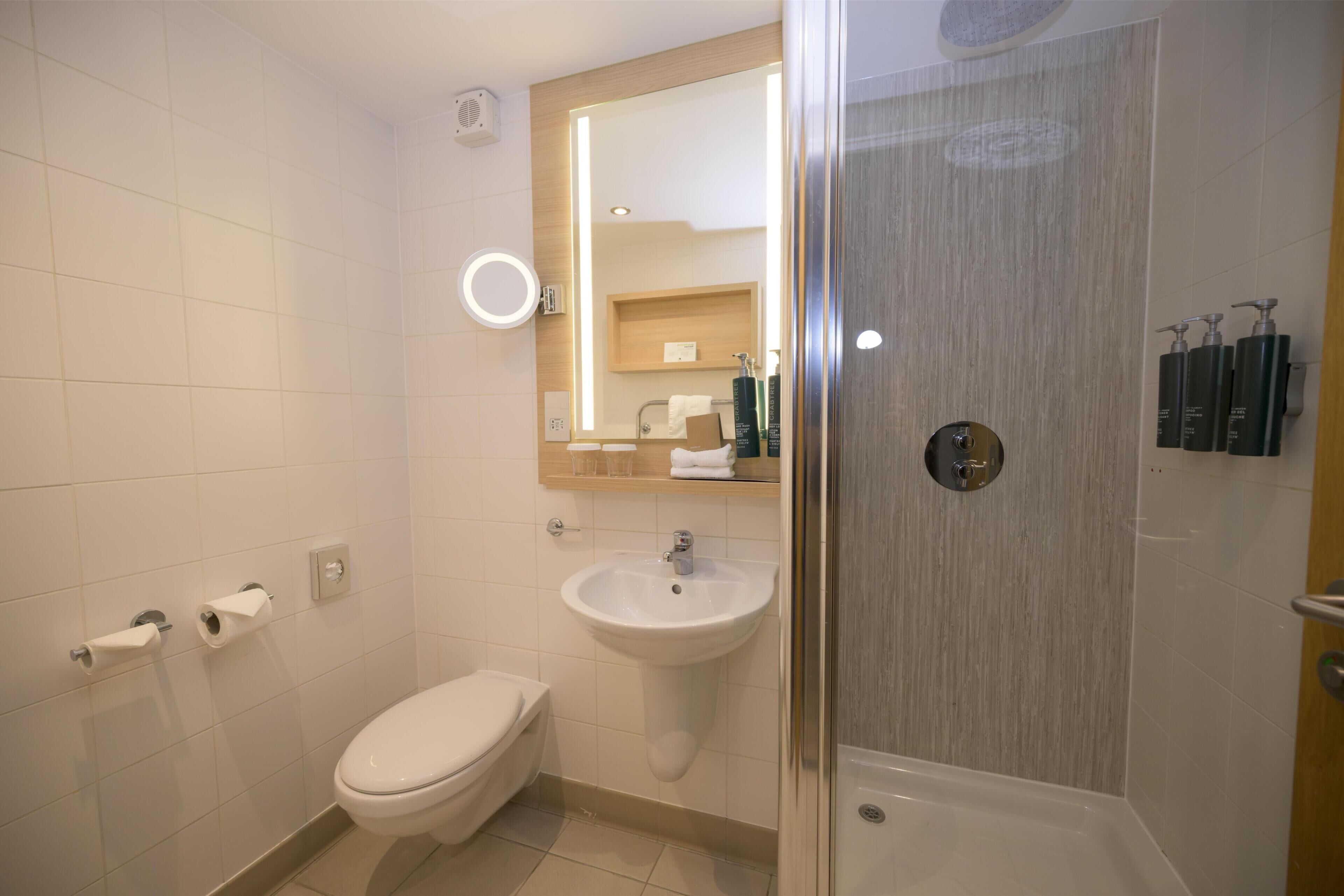 Een moderne badkamer met toilet, wastafel en douche.