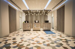 A reception area with a geometric patterned floor, three reception desks, and a blue mat.