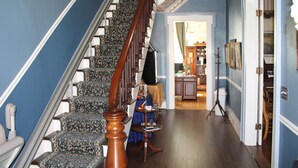 Un escalier recouvert d’une moquette à motifs, avec une main courante en bois et un mur bleu.