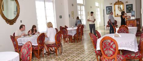 A dining area with multiple tables and chairs, a chandelier, and a tiled floor.