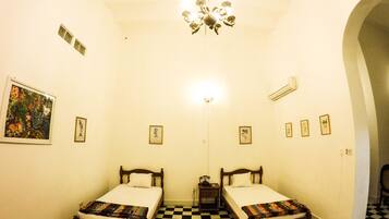 A room with two single beds, a chandelier, and a checkered floor.