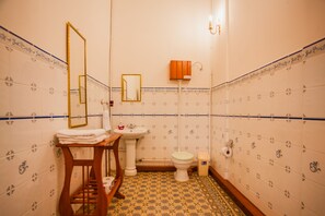 A bathroom with a sink, toilet, and mirror. There is a towel rack and a cabinet. - Apart Hotel Casa Morey (Iquitos)