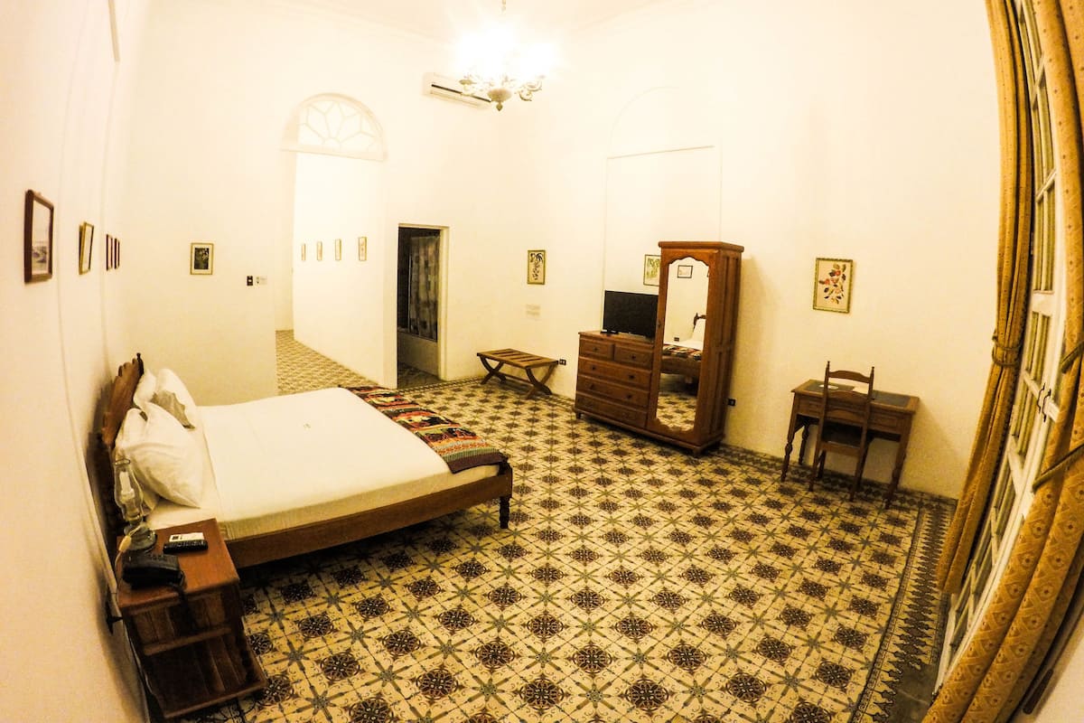A bedroom with a bed, dresser, mirror, and a small table.