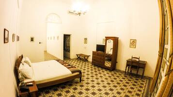Un dormitorio con cama, cómoda, espejo y una mesita.