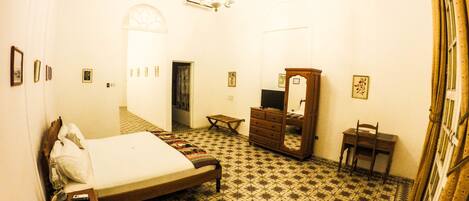 A bedroom with a bed, dresser, mirror, and a small table.