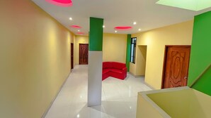 Un pasillo moderno con un sofá rojo, un pilar verde y una puerta de madera.