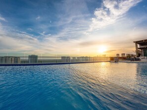 Una piscina infinita en la azotea con el horizonte de la ciudad al fondo.