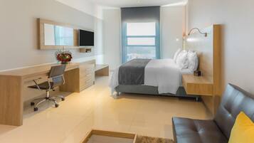 Una habitación de hotel moderna con cama, escritorio, silla, televisor y ventana con vistas a la ciudad.