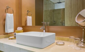 Un baño con un lavabo blanco, un espejo y un perchero para toallas.