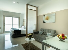 Una habitación de hotel moderna con una cama, sofá y una zona de comedor con fruteros.