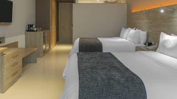 A modern hotel room with two beds, a desk, and a wardrobe.