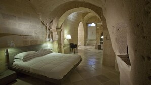 Une pièce comprenant un lit, une table de chevet, une lampe et une porte en arc donnant sur une autre pièce.