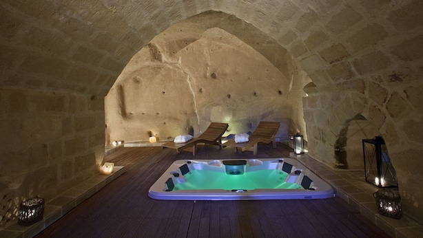 Un spa souterrain doté d’un jacuzzi, de chaises longues en bois et de bougies.