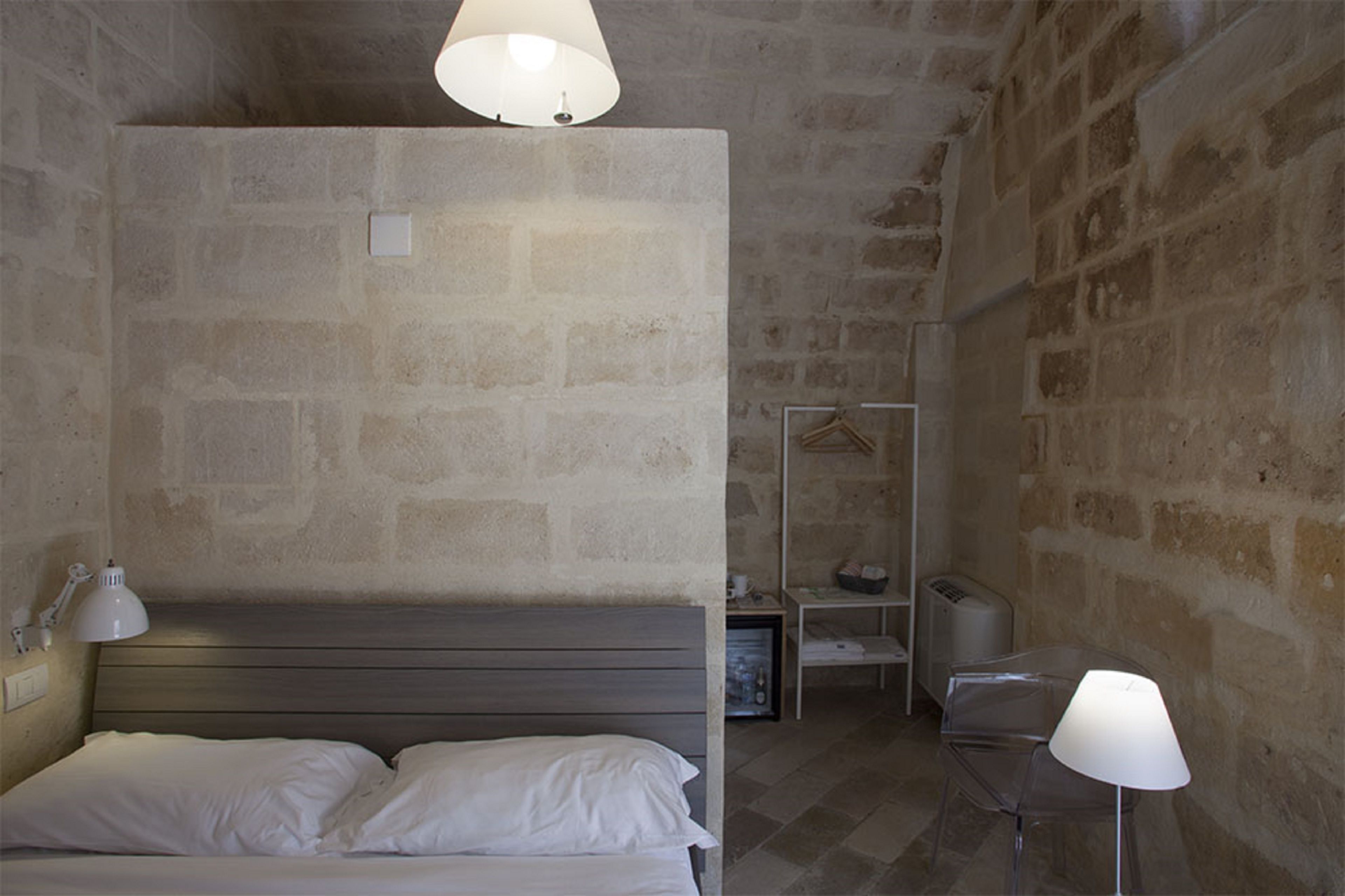 Una camera da letto con un letto, due lampade da comodino, un comodino, un appendiabiti e un tavolino con una lampada.