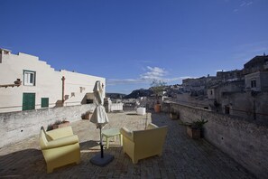 Una terraza en la azotea con sillas amarillas, una mesa y una sombrilla.