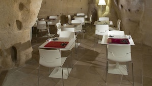 Un espace repas aménagé avec des tables et des chaises, dans un décor qui rappelle l’intérieur d’une grotte.