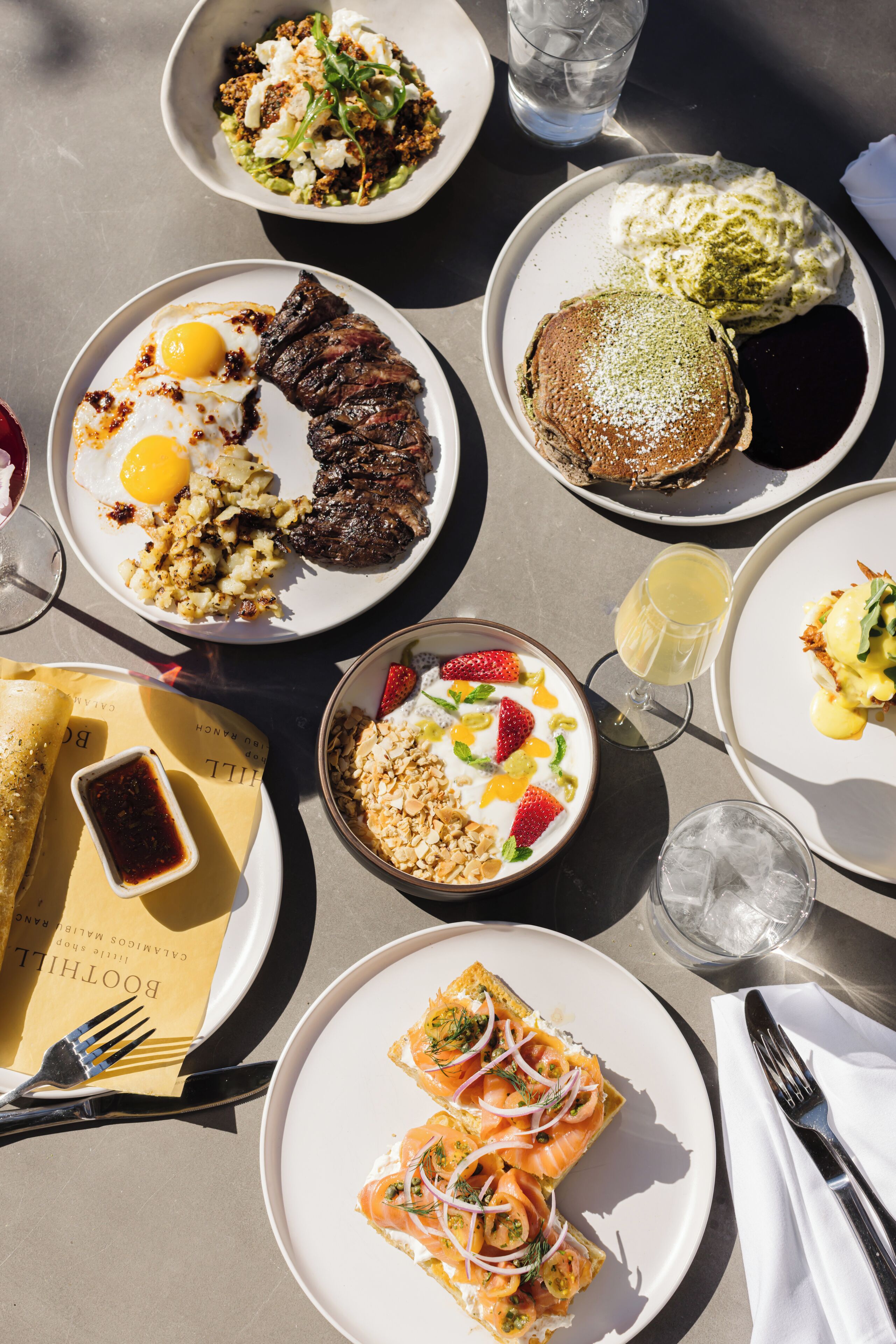 Una mesa con diversos platos, incluyendo bistec, huevos y un postre.