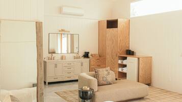 Un dormitorio moderno con techo de madera, una cama grande, un sofá, un aparador y un espejo.