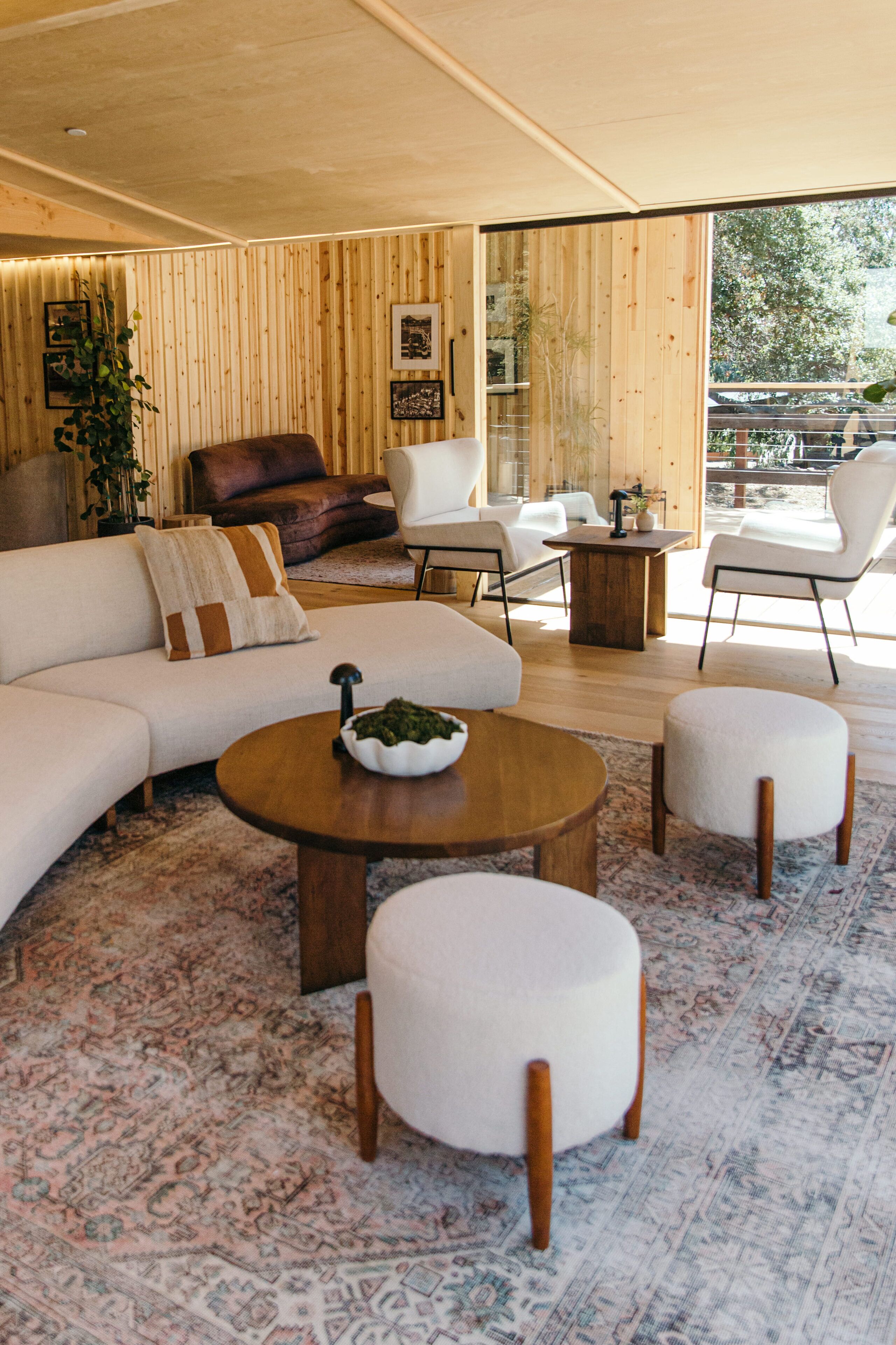 Una sala de estar moderna con un sofá, sillones, pufs y una mesa de centro.