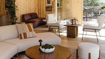 Una sala de estar moderna con un sofá, sillones, pufs y una mesa de centro.