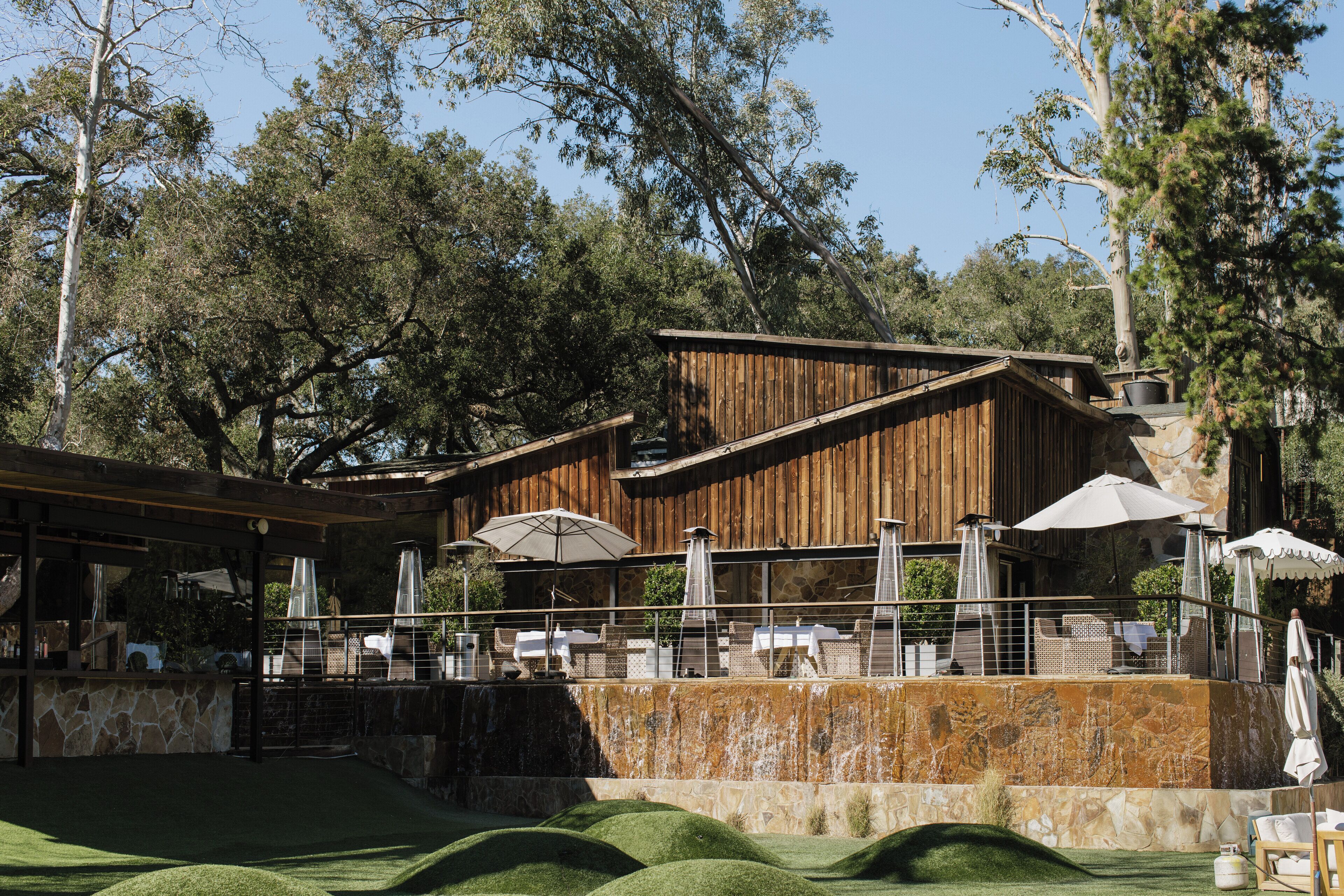 A wooden building with outdoor seating and a stone wall.