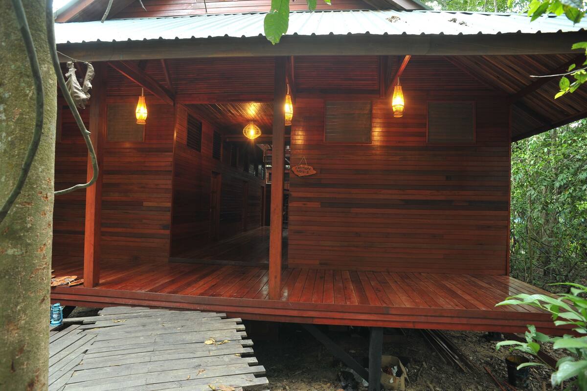 Une cabane en bois avec une véranda, des lampes suspendues et une enseigne indiquant un restaurant.