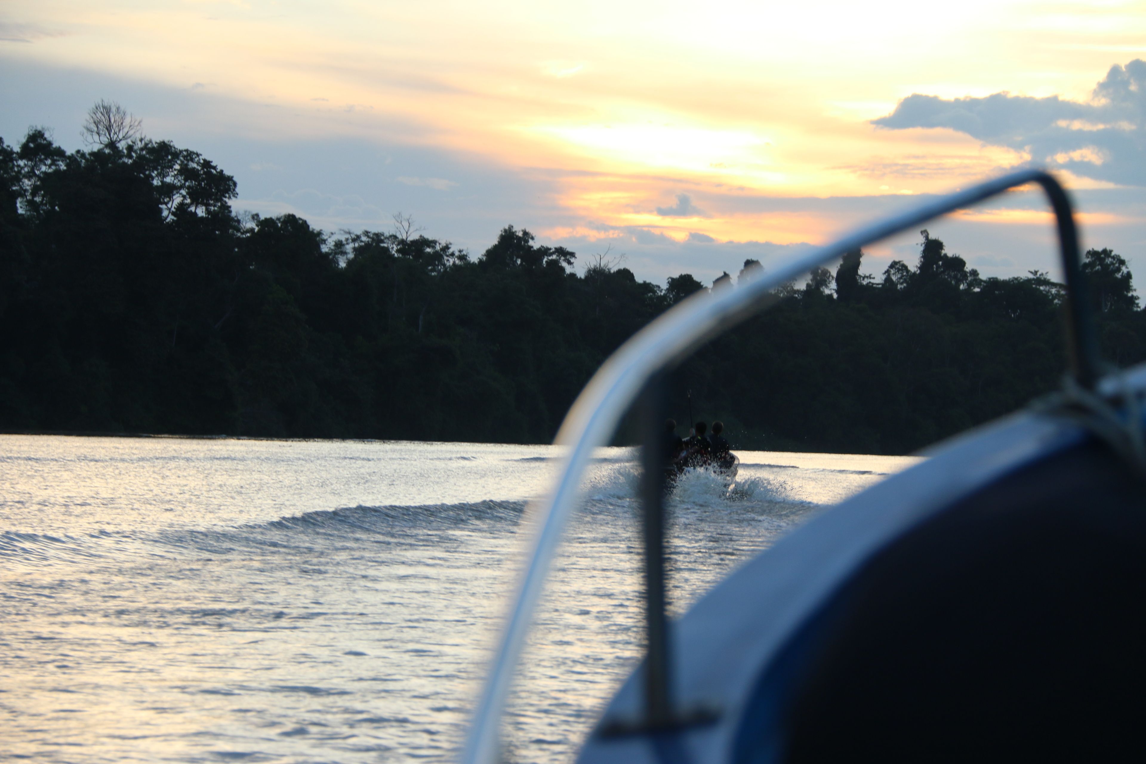 A boat on water with a sunset in the background.
