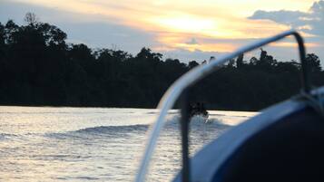 A boat on water with a sunset in the background.