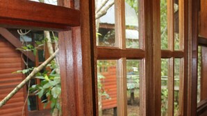 A wooden door with glass panels, leading to an outdoor area with a wooden deck and greenery.