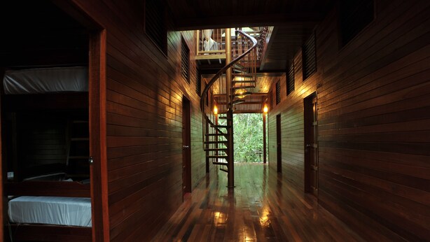 A wooden interior with a spiral staircase leading to a balcony.