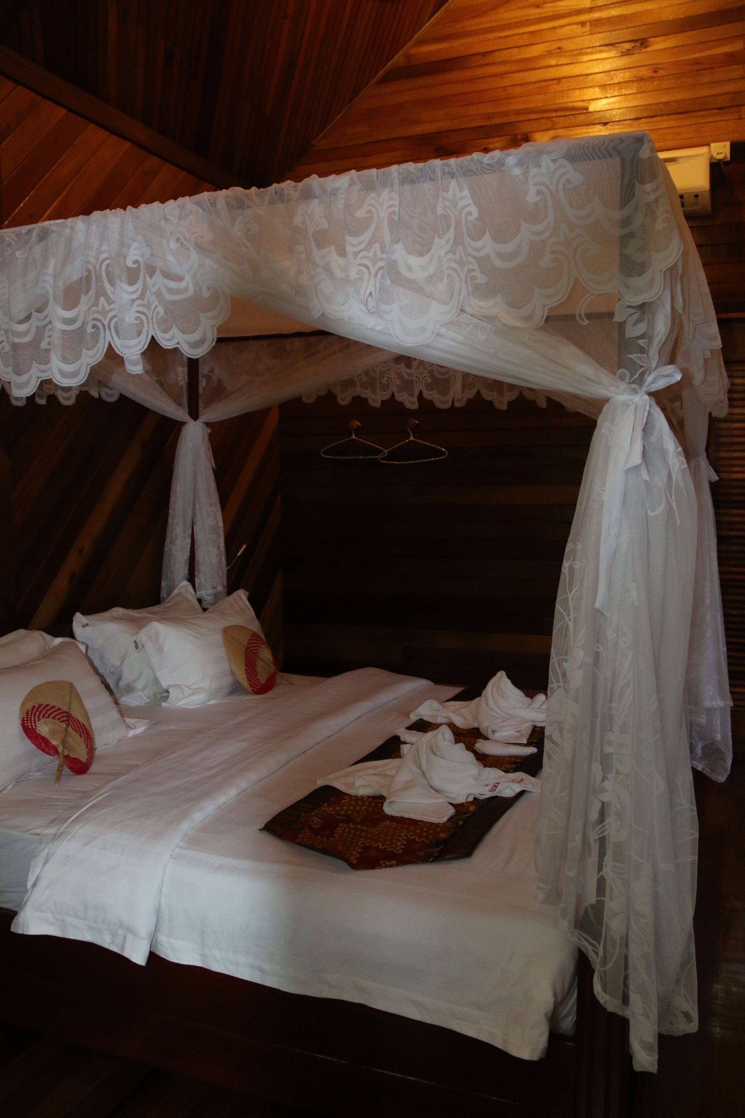 A bed with a canopy, pillows, and a tray with towels.