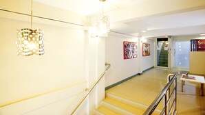 Un corridoio ben illuminato con una scala, un lampadario a parete e un quadro incorniciato.