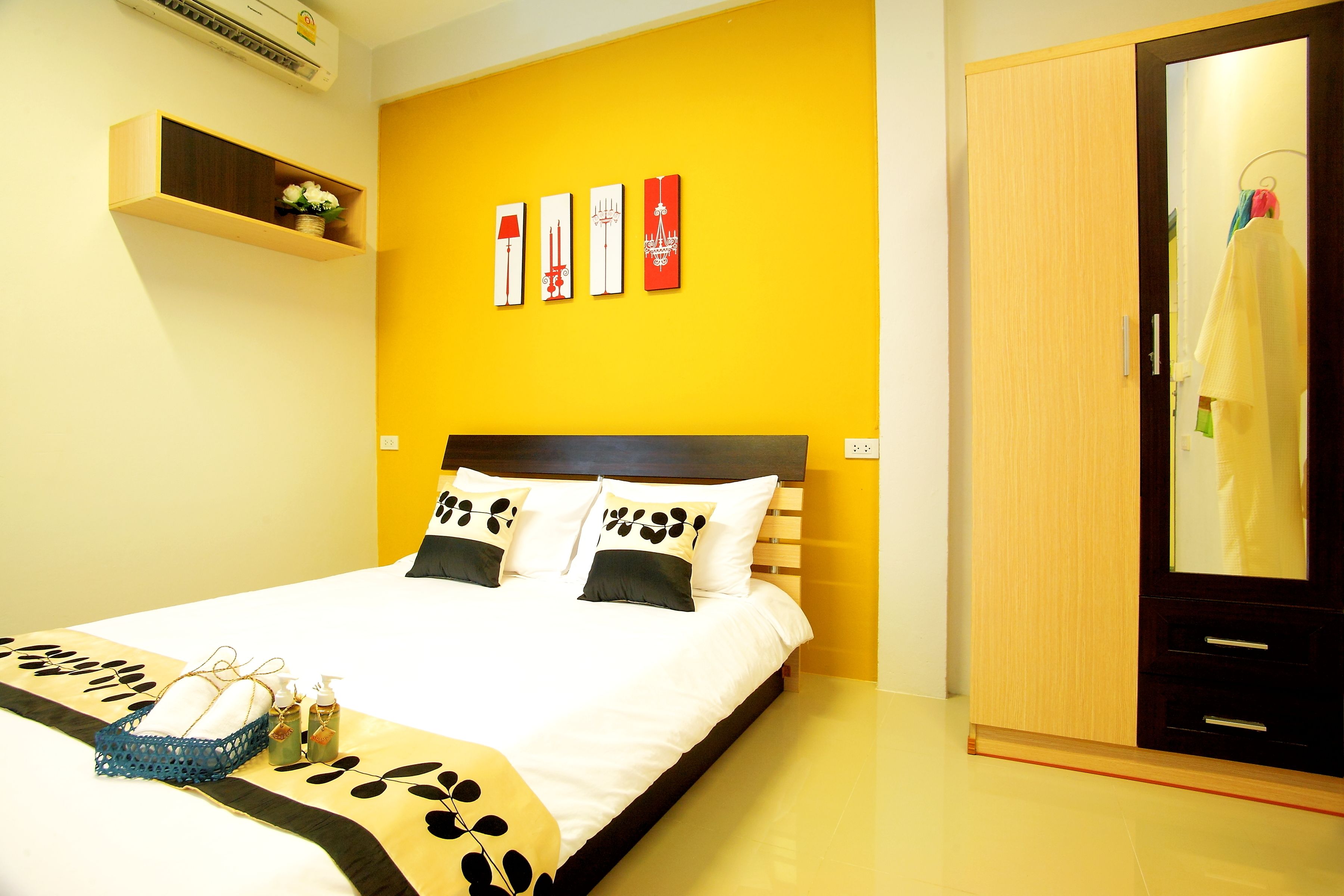 A hotel room with a bed, a wardrobe, and a shelf with decorative items.