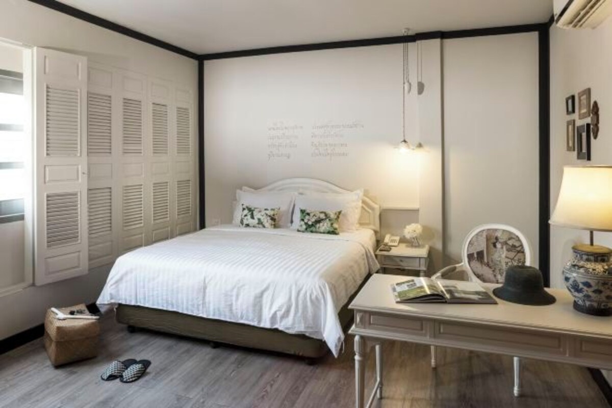 A bedroom with a bed, bedside table, lamp, and a wall with text.