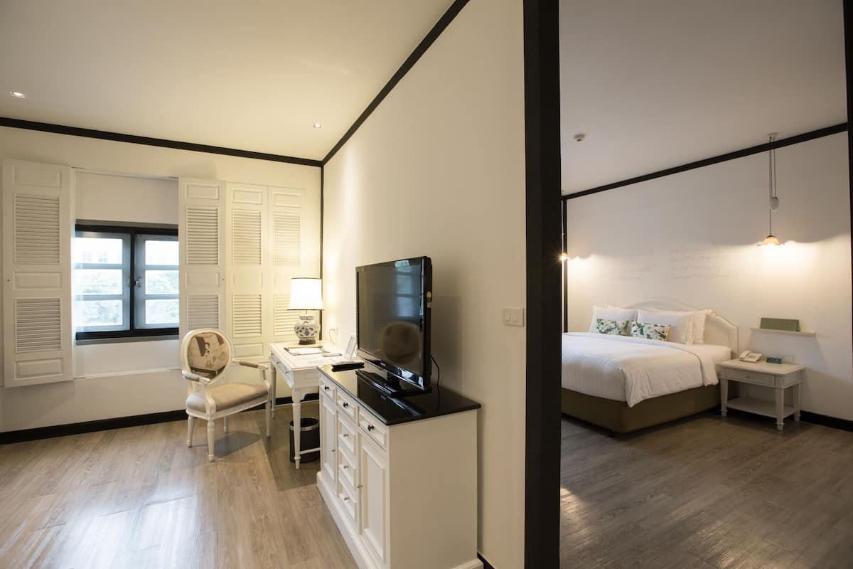 Une chambre à coucher avec un lit, une table de chevet, une lampe et un téléviseur posé sur une commode.