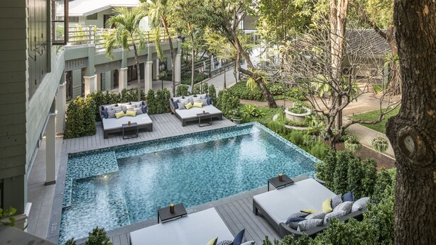 A rooftop pool area with lounge chairs and a small table, surrounded by greenery and trees. - The Raweekanlaya Hotel Bangkok (Bangkok)