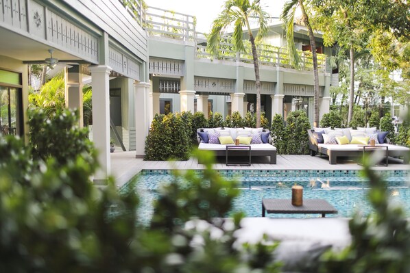 A poolside area with lounge chairs and a small table, surrounded by greenery and a pool. - The Raweekanlaya Hotel Bangkok (Bangkok)